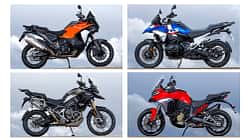 Vier Reiseenduro-Motorräder, BMW R 1300 GS Trophy, Ducati Multistrada V4 S, KTM 1390 Super Adventure S Evo und Triumph Tiger 1200 Rally Pro, fahren nebeneinander auf einem engen Weg. Die Straße führt von einem Aussichtspunkt neben einem Turm weg. Im Hintergrund ist eine weite Aussicht zu sehen. Alle vier Fahrer tragen Motorradbekleidung und Helme.