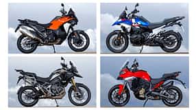 Vier Reiseenduro-Motorräder, BMW R 1300 GS Trophy, Ducati Multistrada V4 S, KTM 1390 Super Adventure S Evo und Triumph Tiger 1200 Rally Pro, fahren nebeneinander auf einem engen Weg. Die Straße führt von einem Aussichtspunkt neben einem Turm weg. Im Hintergrund ist eine weite Aussicht zu sehen. Alle vier Fahrer tragen Motorradbekleidung und Helme.