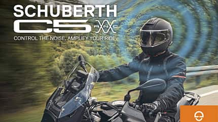 Schuberth C5 ANC, Klapphelm, Motorradhelm, Aktive Geräuschunterdrückung, Tourenhelm, Red Week, Straßenfahrt, Motorradbekleidung, BMW-Motorrad Das Motiv zeigt den Motorradhelm Schuberth C5 ANC im Einsatz während der Fahrt. Als modularer Klapphelm mit aktiver Geräuschunterdrückung (ANC) wird dies durch überlagerte Schallwellen-Grafik sowie den Kampagnentext visualisiert. Es handelt sich um ein Werbemotiv aus der „Red Week“-Kampagne; ein Fahrer auf einer BMW-Reiseenduro ist auf einer Landstraße zu sehen, unten rechts steht das Schuberth‑Logo.