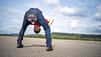 Kleiderpanne, Jeansriss, zerrissene Hose, Rückenansicht Person, Outdoor-Aufnahme, Asphaltfläche, Weitwinkelperspektive, Humoraufnahme, Freizeitkleidung Das Foto zeigt eine Person in Jeans, die sich weit nach vorn beugt; am Gesäß ist die Hose großflächig aufgerissen, was die Aufnahme humoristisch wirken lässt. Die Szene ist im Freien auf einer weiten Asphaltfläche mit tiefer Kameraposition und deutlicher Weitwinkelwirkung aufgenommen; im Hintergrund sind eine Baumreihe und ein bewölkter Himmel zu sehen.