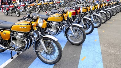 Große Reihe von Honda CB 750 Four Motorrädern bei einem Jubiläumsevent, zahlreiche Besucher und Zelte im Hintergrund.