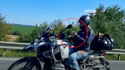 Motorradfahrer auf der Autobahn, mit beiden Händen am Smartphone