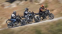 Drei Motorräder im direkten Vergleich: QJMOTOR SRK 600 PRO, Suzuki SV 650 und Yamaha MT 07 (alt) fahren nebeneinander auf einer Landstraße. Die Fahrer tragen Motorradschutzkleidung und Helme. Die Szene zeigt eine dynamische Fahrsituation im Freien.