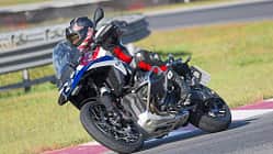 Reiseenduro-Motorrad in Kurvenfahrt auf Rennstrecke, Fahrer mit Schutzkleidung und Helm.