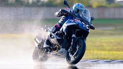 Reiseenduro, Motorrad, Kurvenfahrt, Nassstrecke, Fahrdynamik, Motorradtechnik, Fahrer, Wasser, Fahrtraining Motorradfahrer auf einer Reiseenduro fährt auf nasser Strecke und wirbelt Wasser auf.