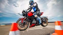 Triumph Trident 800 Motorrad bei dynamischer Fahrprobe mit Fahrer im Slalom zwischen Pylonen.