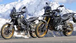Zwei Mid-Adventure-Motorräder asiatischer Hersteller vor schneebedeckten Alpenbergen, aufgenommen beim Alpenmaster-Event 2026.