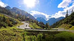 Motorradfahrer in Kurve auf Passstraße am Hahntennjoch in alpiner Landschaft bei Sonnenschein.