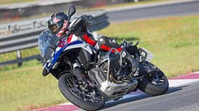 Reiseenduro-Motorrad in Kurvenfahrt auf Rennstrecke, Fahrer mit Schutzkleidung und Helm.