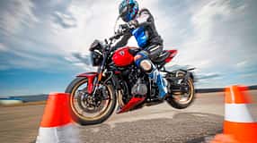 Triumph Trident 800 Motorrad bei dynamischer Fahrprobe mit Fahrer im Slalom zwischen Pylonen.