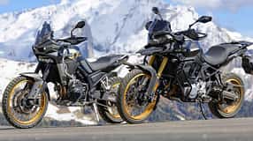 Zwei Mid-Adventure-Motorräder asiatischer Hersteller vor schneebedeckten Alpenbergen, aufgenommen beim Alpenmaster-Event 2026.