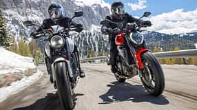 Zwei Mid-Naked-Motorräder beim Alpenmaster 2024 auf einer Passstraße in den Alpen, beide Fahrer mit Motorradbekleidung und Helmen, verschneite Berge im Hintergrund.