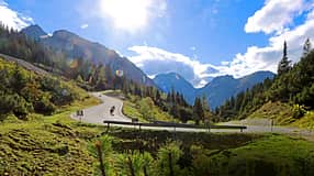 Motorradfahrer in Kurve auf Passstraße am Hahntennjoch in alpiner Landschaft bei Sonnenschein.
