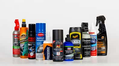 Gruppenbild verschiedener Kunststoffpflegeprodukte in Flaschen und Sprühdosen vor weißem Hintergrund.