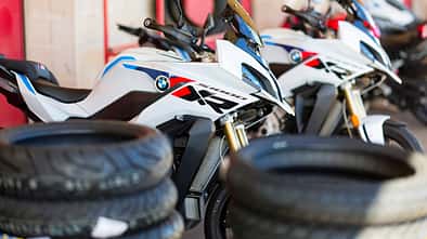 BMW S 1000 XR Motorräder bei einem Reifentest in Rom, umgeben von Motorradreifenstapeln.