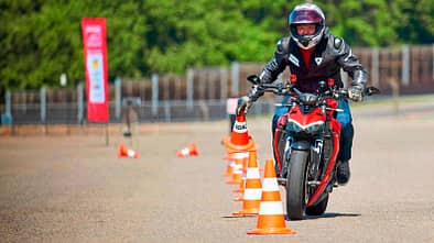 Motorradfahrer bei einem ADAC-Motorrad-Sicherheitstraining auf dem Sachsenring, fährt Slalom zwischen Pylonen.