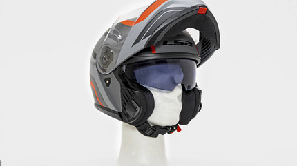 Der Motorradhelm LS2 FF908 Strobe II ist auf einem neutralen Hintergrund abgebildet. Das Visier ist geöffnet, das Sonnenvisier heruntergeklappt. Der Helm ist grau mit orangen und schwarzen Akzenten und steht auf einem weißen Dummy-Kopf.