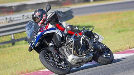 Reiseenduro-Motorrad in Kurvenfahrt auf Rennstrecke, Fahrer mit Schutzkleidung und Helm.