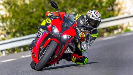 QJM SRK 800 RR, Superbike, 2024, Sportmotorrad, Kurvenfahrt, Motorradtechnik, Rennstrecke, Fahrer, Racing-Lederkombi, Straßenmotorrad QJM SRK 800 RR in Kurvenfahrt auf der Landstraße, Fahrer in Racing-Lederkombi.