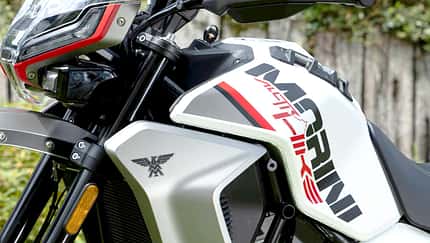 Detailaufnahme eines Adventure-Motorrads mit dem Schriftzug 'Morini' und 'X-Cape 650' auf dem Tank. Das Motorrad steht im Freien, im Vordergrund sind Frontverkleidung, Windschild und Motor zu sehen.