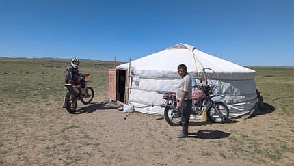 Jurte, Motorrad, Steppe, Mongolei, Motorradreise, Nomaden, Enduro, Fernreise, Abenteuer, Tradition Motorradfahrer und Einheimischer vor einer Jurte in einer weiten Steppe, zwei Motorräder sichtbar.