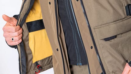 Modeka Atlaz, Motorradjacke, Motorradbekleidung, Textiljacke, Adventure-Jacke, Protektorenjacke, Multilayer-System, Motorrad-Ausrüstung, Fahrerbekleidung Detailaufnahme einer geöffneten Motorradjacke Modeka Atlaz, getragen von einer Person. Die Jacke zeigt verschiedene Materialien, Reißverschlüsse und das Innenfutter.