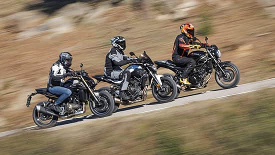 Drei Motorräder im direkten Vergleich: QJMOTOR SRK 600 PRO, Suzuki SV 650 und Yamaha MT 07 (alt) fahren nebeneinander auf einer Landstraße. Die Fahrer tragen Motorradschutzkleidung und Helme. Die Szene zeigt eine dynamische Fahrsituation im Freien.