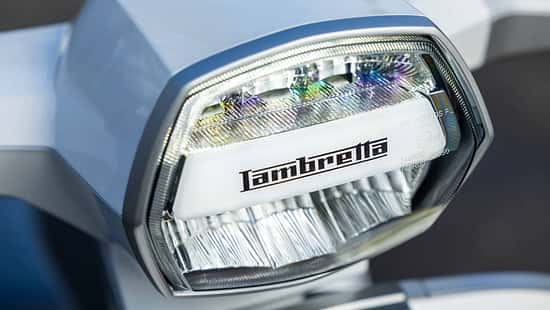 Detailaufnahme des Frontscheinwerfers eines Lambretta G350 Rollers mit deutlich sichtbarem Markenlogo.