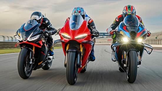 Drei Superbikes der Modellgeneration 2026 fahren nebeneinander auf der Rennstrecke in Valencia. Die Motorräder werden von Fahrern in voller Rennkleidung pilotiert und befinden sich in Schräglage auf der Start-Ziel-Geraden.