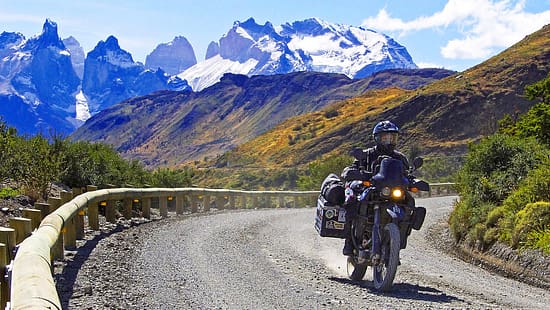 Reiseenduro-Motorrad auf Schotterstraße in Patagonien, Chile, mit schneebedeckten Bergen, den Anden, im Hintergrund.