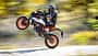 KTM 990 Duke R, Naked Bike, wird auf dem Hinterrad gefahren (Wheelie), Fahrer in Motorradkombi, dynamische Straßenaufnahme.