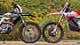Enduro, Motorrad, Geländemotorrad, Offroad, Motorradtechnik, Windenergie, Wald, Motorsport, Zweirad, Natur, Triumph TF 450-E, Stark Varg EX Zwei Enduro-Motorräder, die Stark Varg EX und die Triumph TF 450-E parken frontal gegenüber im Gelände vor bewaldetem Hintergrund und Windrädern, sodass sich die Vorderreifen berühren. Aufnahme aus der Seitenansicht.