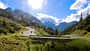 Motorradfahrer in Kurve auf Passstraße am Hahntennjoch in alpiner Landschaft bei Sonnenschein.
