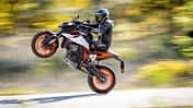 KTM 990 Duke R, Naked Bike, wird auf dem Hinterrad gefahren (Wheelie), Fahrer in Motorradkombi, dynamische Straßenaufnahme.